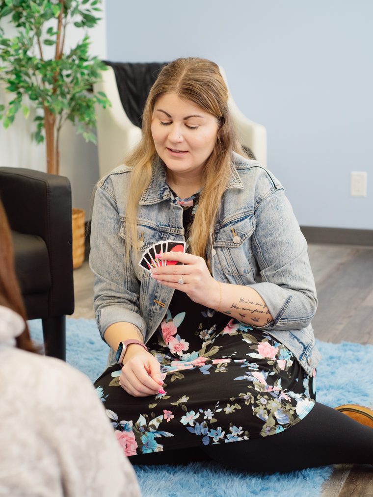 A counsellor sitting on the floor playing cards with a client
